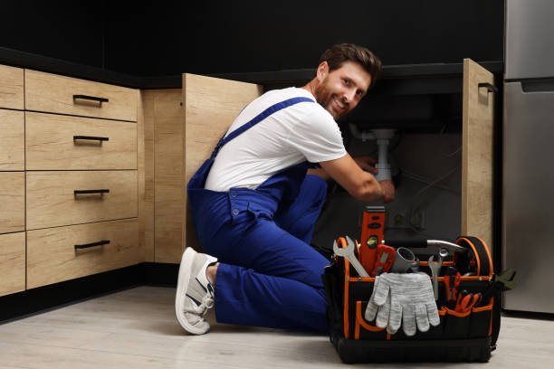 How to become a Plumber in UK 7 Professional plumber in uniform fixing sink indoors