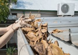 Gutter Cleaning Cost: Complete Pricing Guide for Homeowners 2 gutter cleaning on a difficult-to-access area of a home